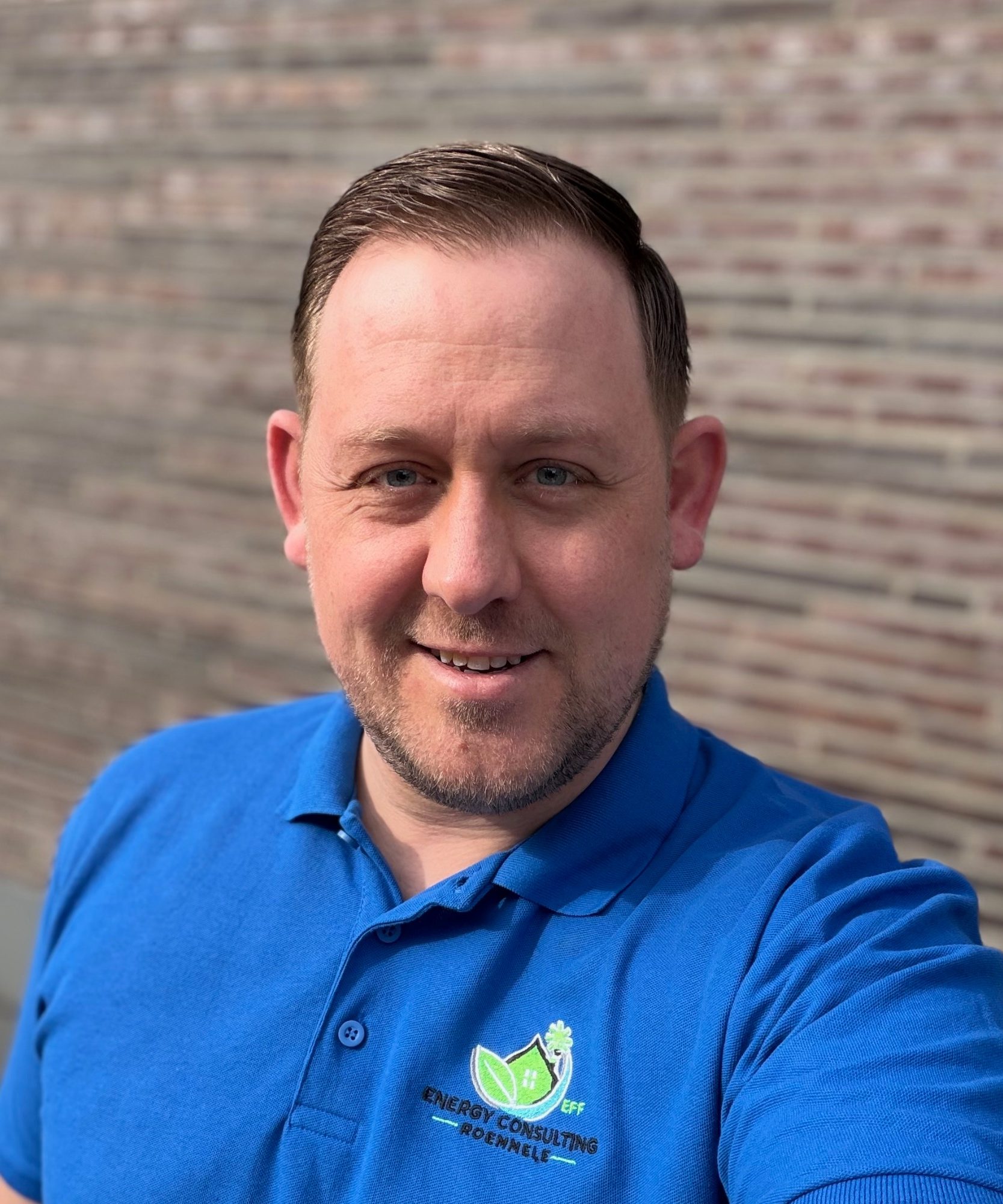 Mann mit kurzen Haaren und Polo-Shirt steht in einem modernen Raum mit Fenstern.